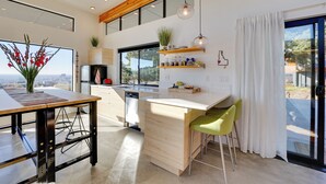 A modern kitchen with a wooden ceiling, a large window, and a view of the city. - Luxe, Modern Studio w/ Sweeping City Views! (Boise)
