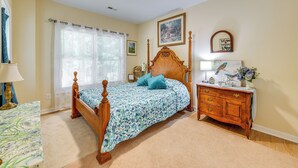 A bedroom with a four-poster bed, a wooden dresser, a nightstand, and a window with sheer curtains. - Charming Charlottesville Apt w/ Outdoor Space! (Charlottesville)