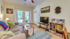 A living room with a sofa, coffee table, bookshelf, and a television. - Charming Charlottesville Apt w/ Outdoor Space! (Charlottesville)