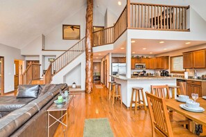 Relax in this open living area with a central staircase, leather sofa, dining table for four, and modern kitchen.