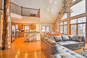 Experience the open-plan living space with a kitchen, dining area, and comfortable sofa set, featuring a unique tree trunk sculpture.