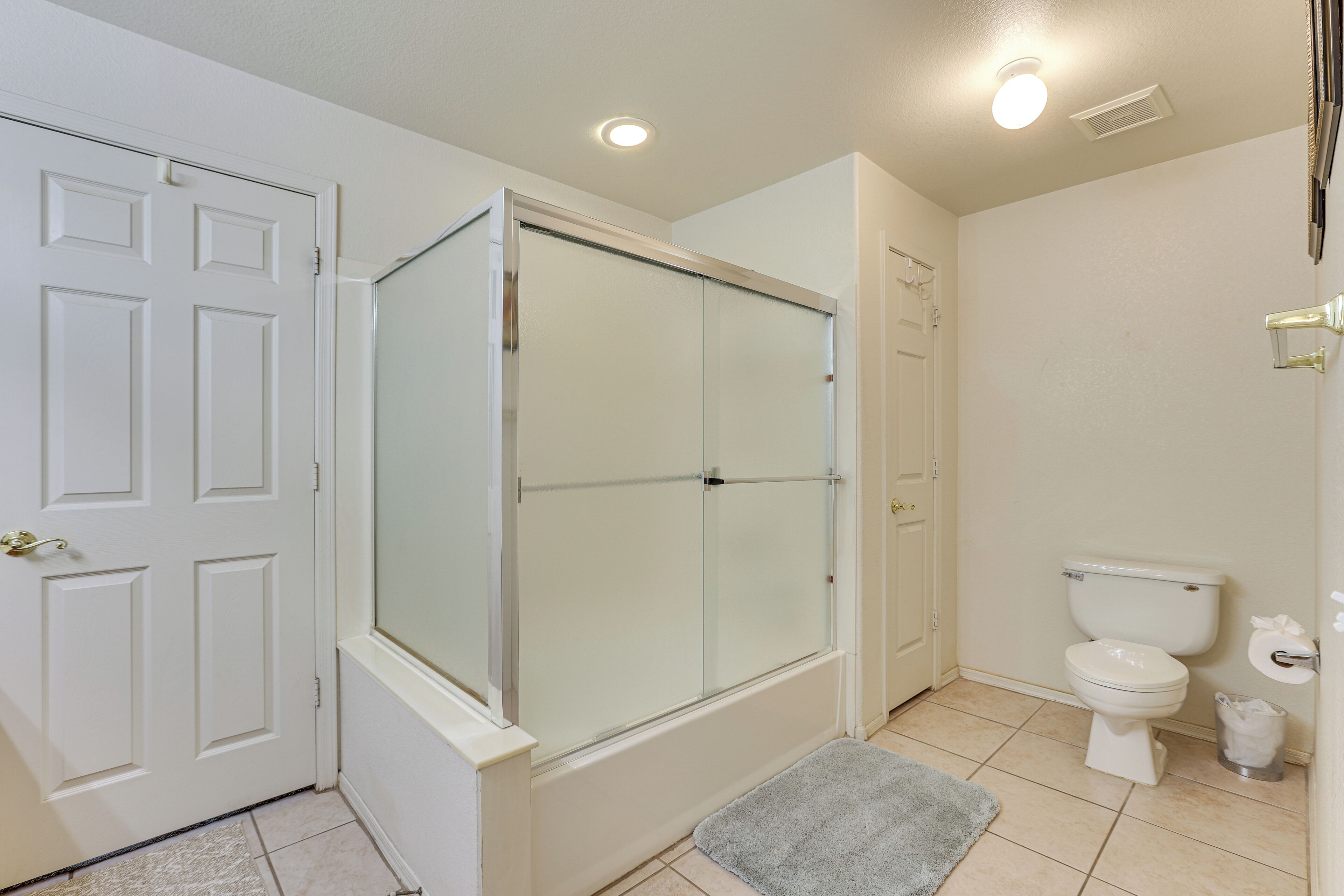A bathroom with a glass-enclosed shower, a toilet, and a white door.
