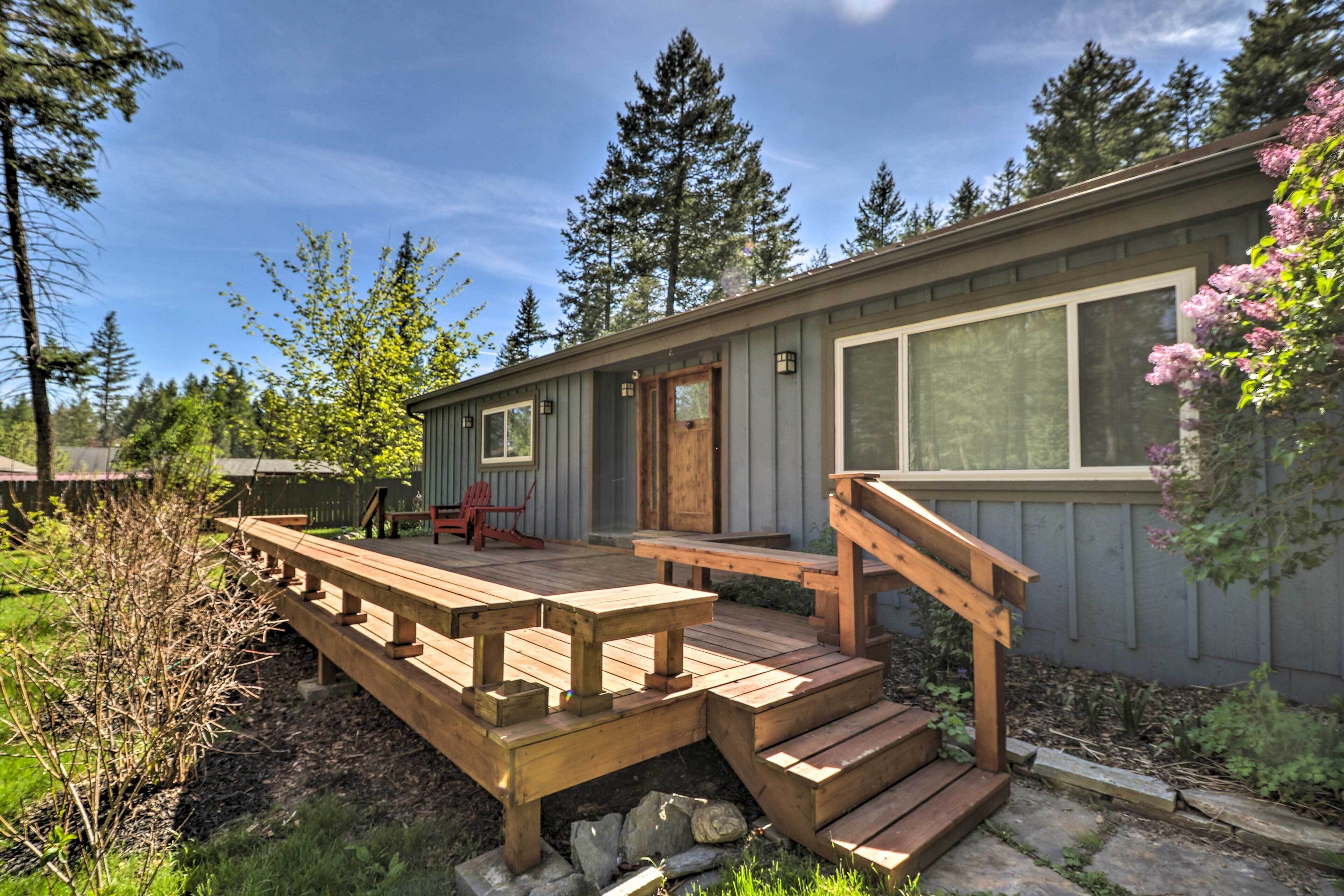 A wooden deck with benches, a wooden staircase, and a door leading to a covered porch.