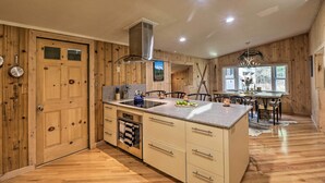 A kitchen with wooden walls, a built-in stove, and a dining area with a table and chairs. - Spacious Whitefish Getaway: Hike, Ski, Bike & More (Whitefish)
