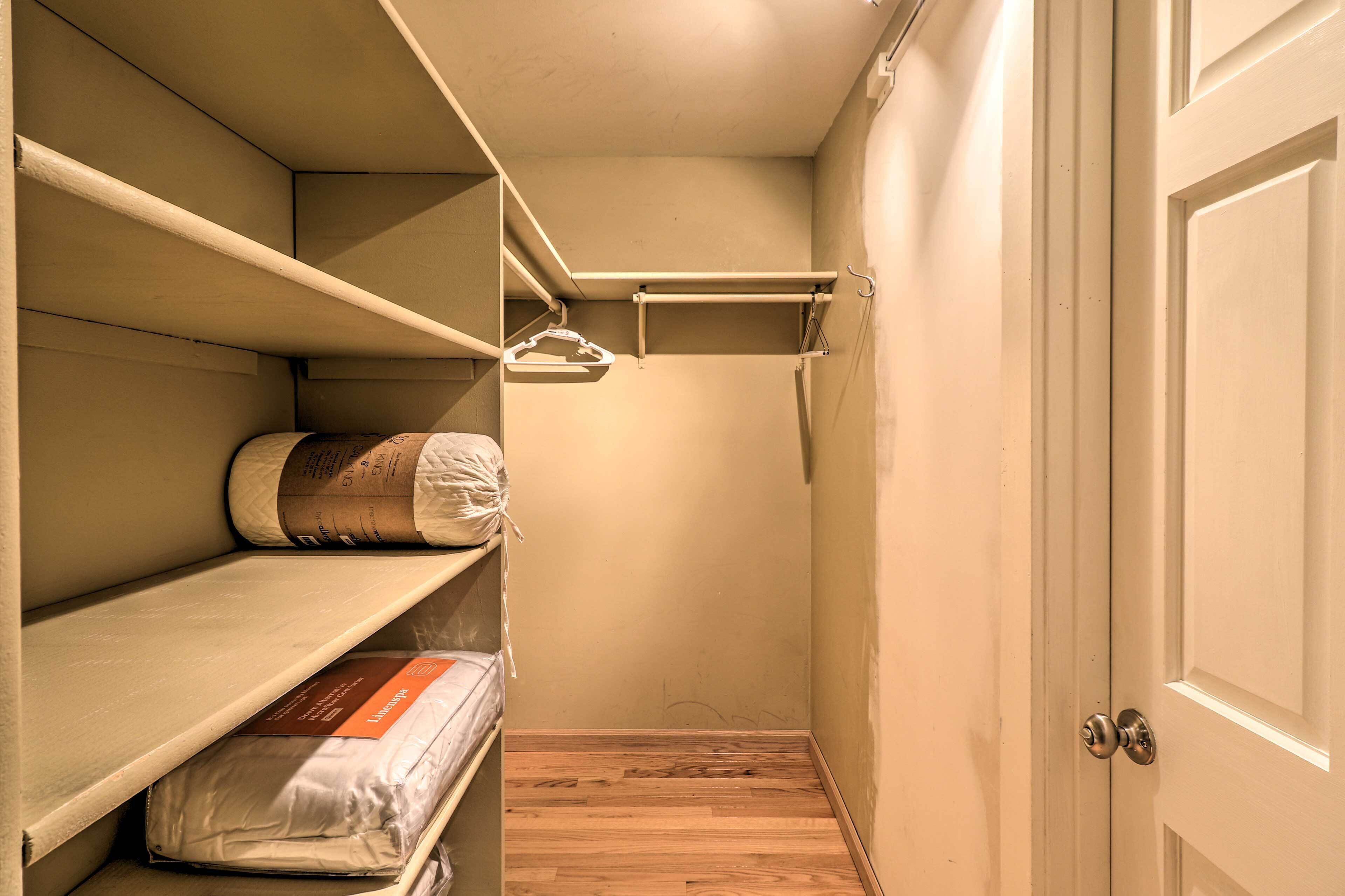 A closet with shelves and hanging space, a door, and a wooden floor.