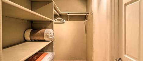 A closet with shelves and hanging space, a door, and a wooden floor.