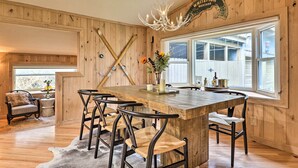 A rustic dining area with a wooden table, black chairs, and a chandelier. - Spacious Whitefish Getaway: Hike, Ski, Bike & More (Whitefish)