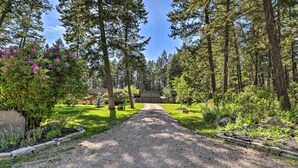 A gravel driveway leading to a house surrounded by tall trees and a well-maintained lawn. - Spacious Whitefish Getaway: Hike, Ski, Bike & More (Whitefish)