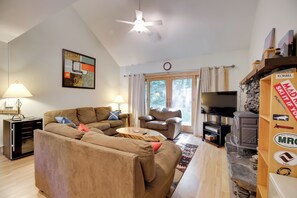 Una sala de estar con sofá, sillones, mesa de centro, chimenea y televisor.