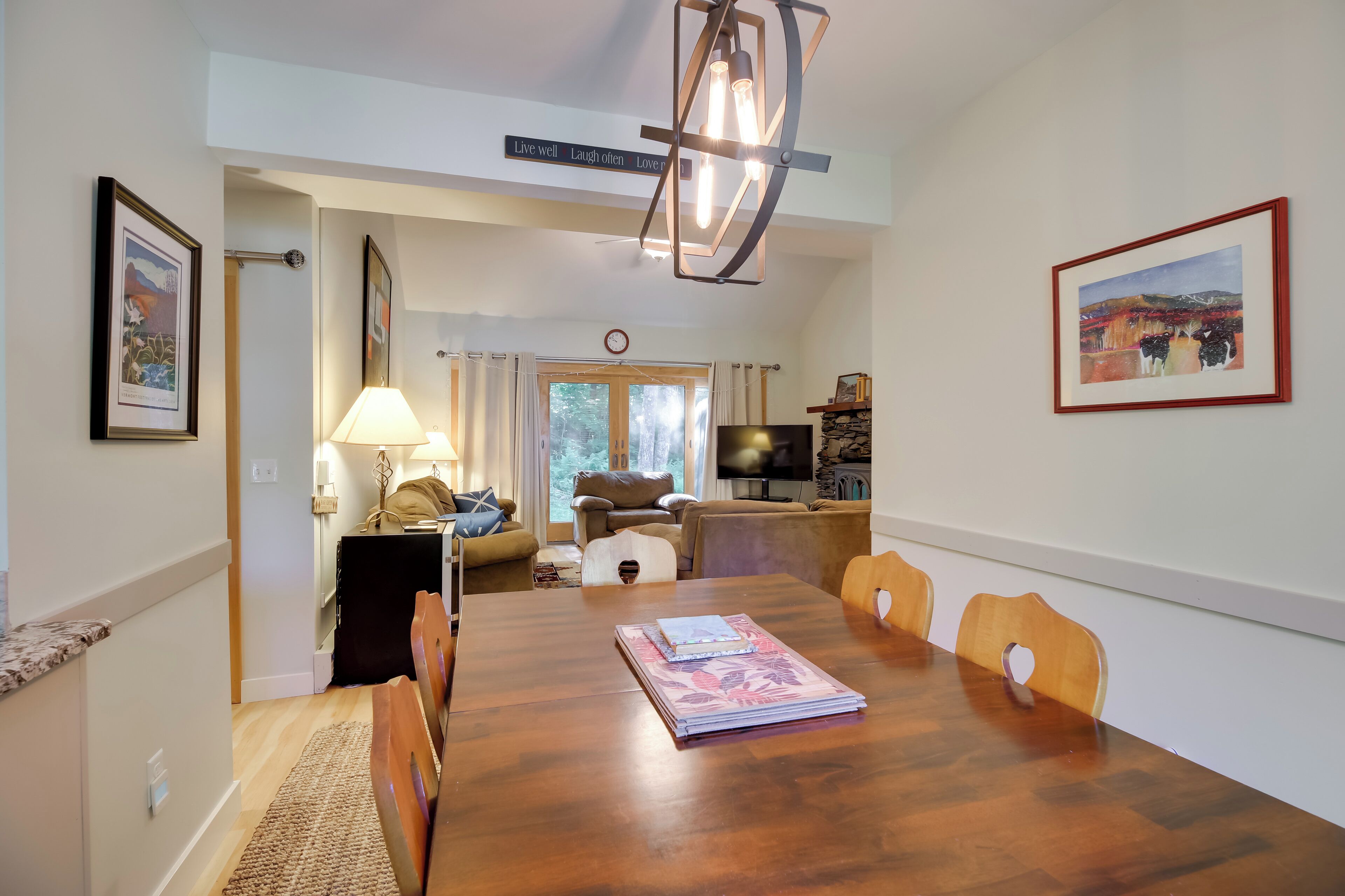 A dining area with a wooden table, chairs, a television, and a painting on the wall.