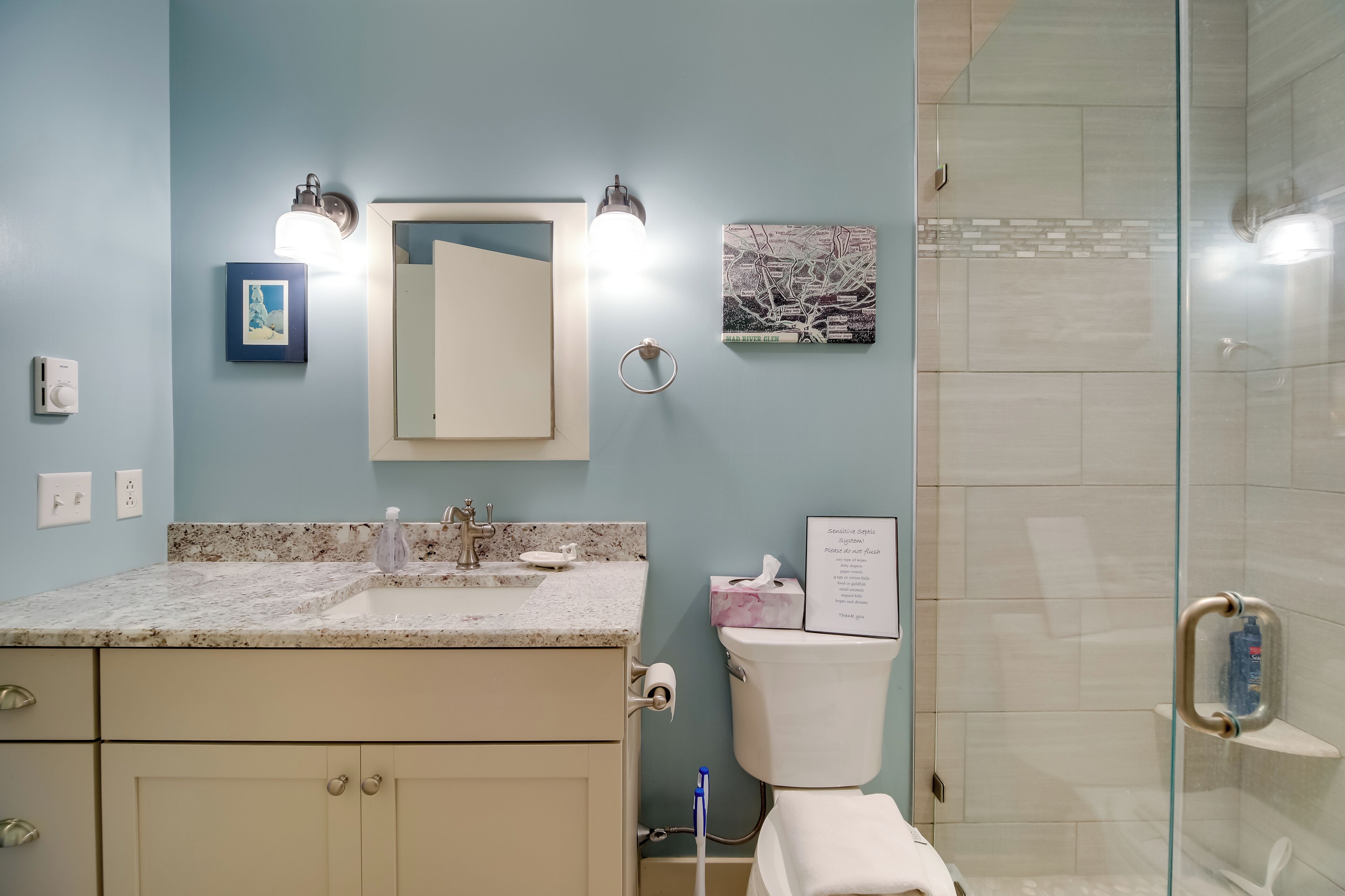 A bathroom with a sink, mirror, toilet, and shower.