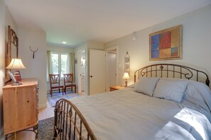 Un dormitorio con cama, mesita de noche, lámpara, cómoda de madera y un cuadro en la pared.