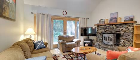 A living room with a sofa, armchair, coffee table, and a fireplace with a stone wall.