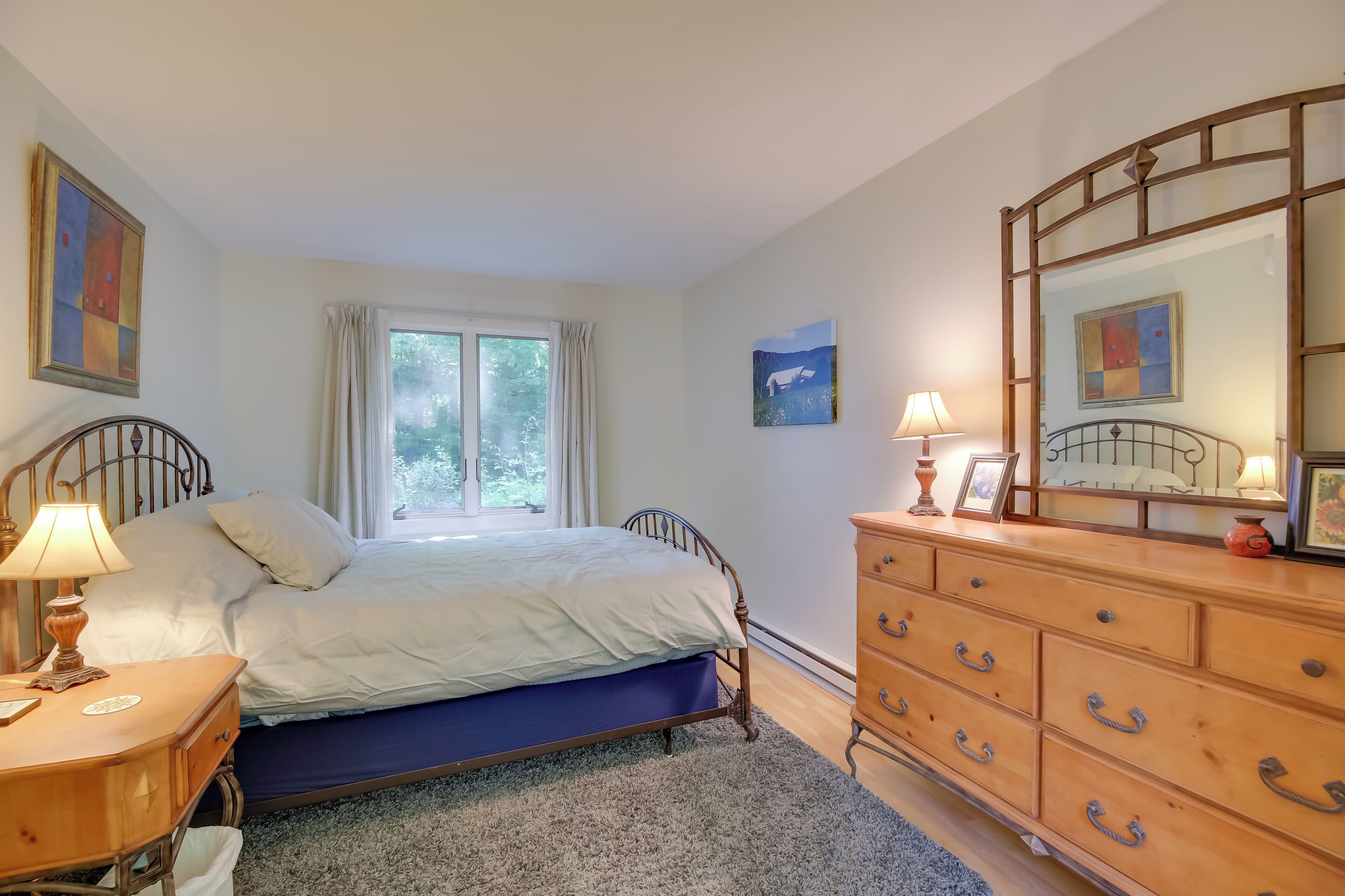 Ein Schlafzimmer mit Bett, Kommode und Fenster.