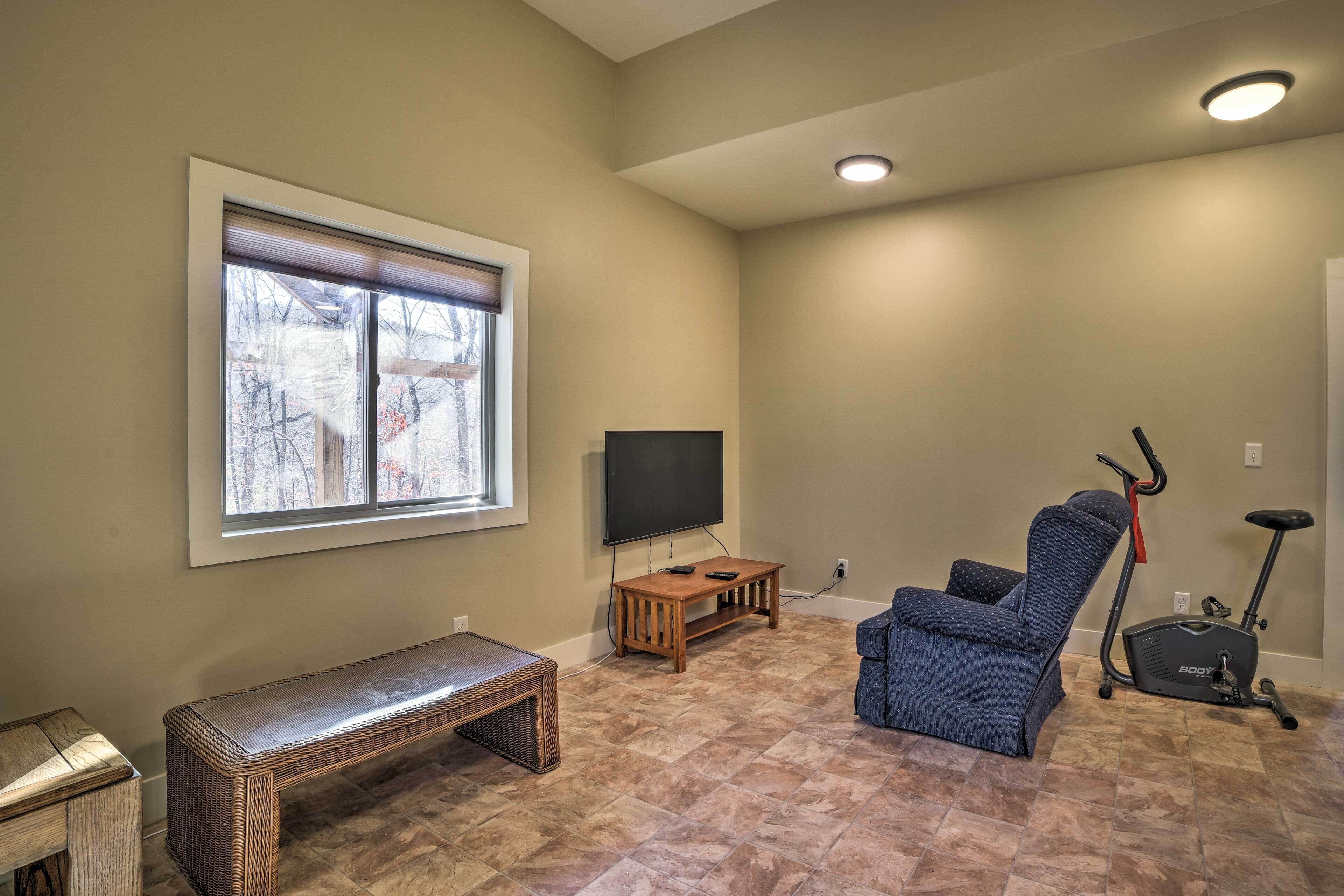 A living room with a TV, exercise bike, and a bench.