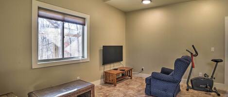A living room with a TV, exercise bike, and a bench.