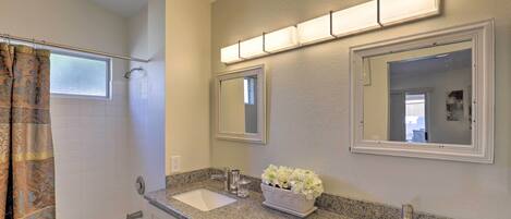 A bathroom with a bathtub, two sinks, a shower, and a mirror with lights.