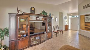 A spacious living room with a large wooden entertainment center, a flat-screen TV, and a dining area with a table and chairs. - North Tucson Home w/ Patio by Catalina State Park! (Tucson)