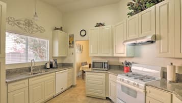 A kitchen with white cabinets, a stainless steel microwave, a gas stove, and a sink.