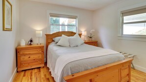 A bedroom with a wooden bed, nightstands, a window, and a ceiling fan.