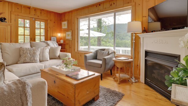 A cozy living room with a fireplace, wooden walls, a sofa, a coffee table, and a television.