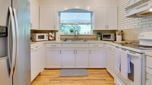 A modern kitchen with white cabinets, a stainless steel refrigerator, a microwave, and an oven.