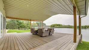 Un terrazzo in legno con mobili da esterno e vista su un lago.
