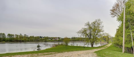 A gravel path leading to a body of water with trees and a utility pole.