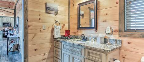 A wooden-paneled bathroom with a sink, mirror, and towel rack.