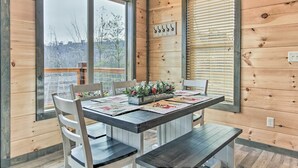 A wooden interior with a dining table set for four, surrounded by white chairs. - Smoky Mountain Hideaway w/ Hot Tub, Deck & Views! (Gatlinburg)