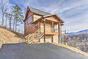 A two-story log cabin with a balcony and a stone foundation, surrounded by a mountainous landscape. - Smoky Mountain Hideaway w/ Hot Tub, Deck & Views! (Gatlinburg)