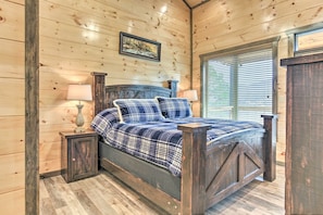 A wooden-paneled bedroom with a bed, two bedside tables, and a window with blinds. - Smoky Mountain Hideaway w/ Hot Tub, Deck & Views! (Gatlinburg)