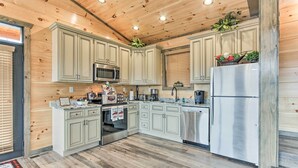 A modern kitchen with light wood cabinets, stainless steel appliances, and a wooden ceiling. - Smoky Mountain Hideaway w/ Hot Tub, Deck & Views! (Gatlinburg)