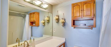 A bathroom with a sink, mirror, wooden cabinets, and a toilet.