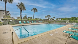 Une piscine avec des chaises longues et des palmiers.