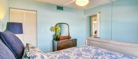 Un dormitorio con cama, cómoda, espejo y ventilador de techo.