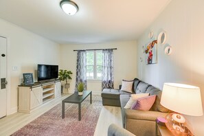 Uma sala de estar com televisão, sofá e abajur.