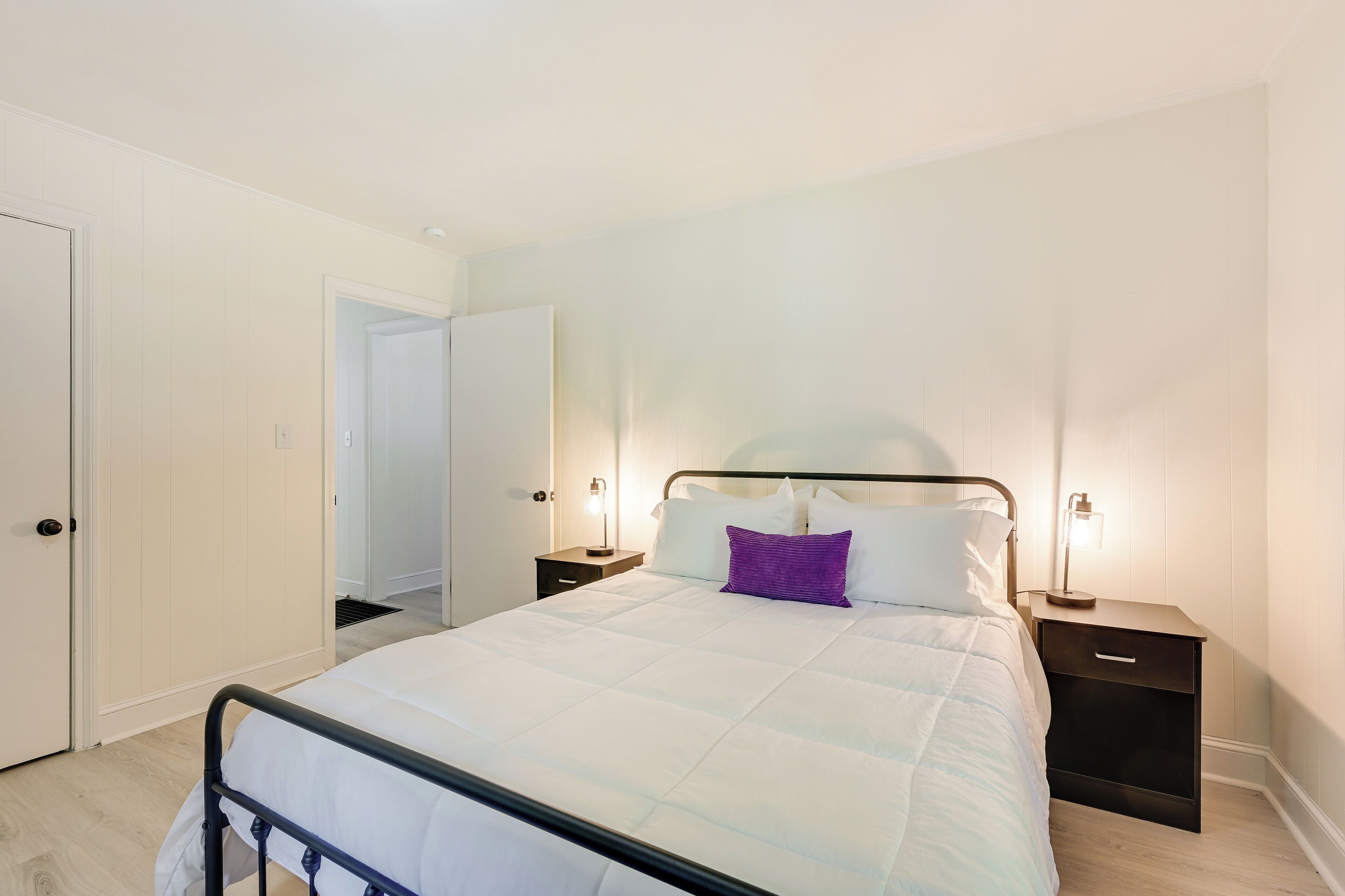 A bedroom with a bed, nightstands, and a door.