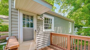 A wooden deck with a bench, a door with a screen, and a window with a light fixture. - Winston-salem Vacation Rental ~ 3 Mi to Downtown! (Winston-Salem)