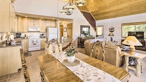 A spacious kitchen with wooden cabinets, a dining area with a wooden table, and a living room with a sofa and TV. - Quiet Fairplay Cabin w/ Rocky Mountain Views! (Fairplay)