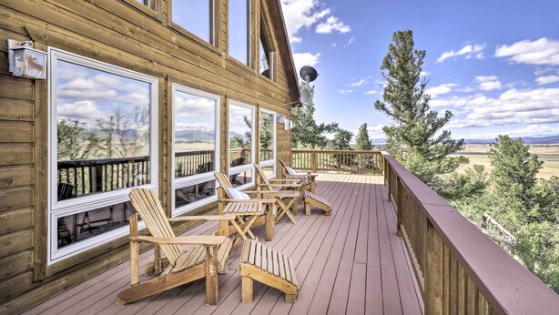 A wooden deck with Adirondack chairs and large windows overlooking a scenic landscape. - Quiet Fairplay Cabin w/ Rocky Mountain Views! (Fairplay)