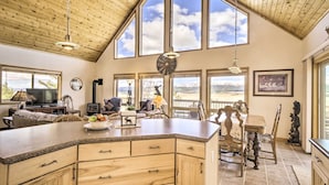 A spacious kitchen with a large island, wooden cabinetry, and a dining area with a wooden table and chairs. - Quiet Fairplay Cabin w/ Rocky Mountain Views! (Fairplay)