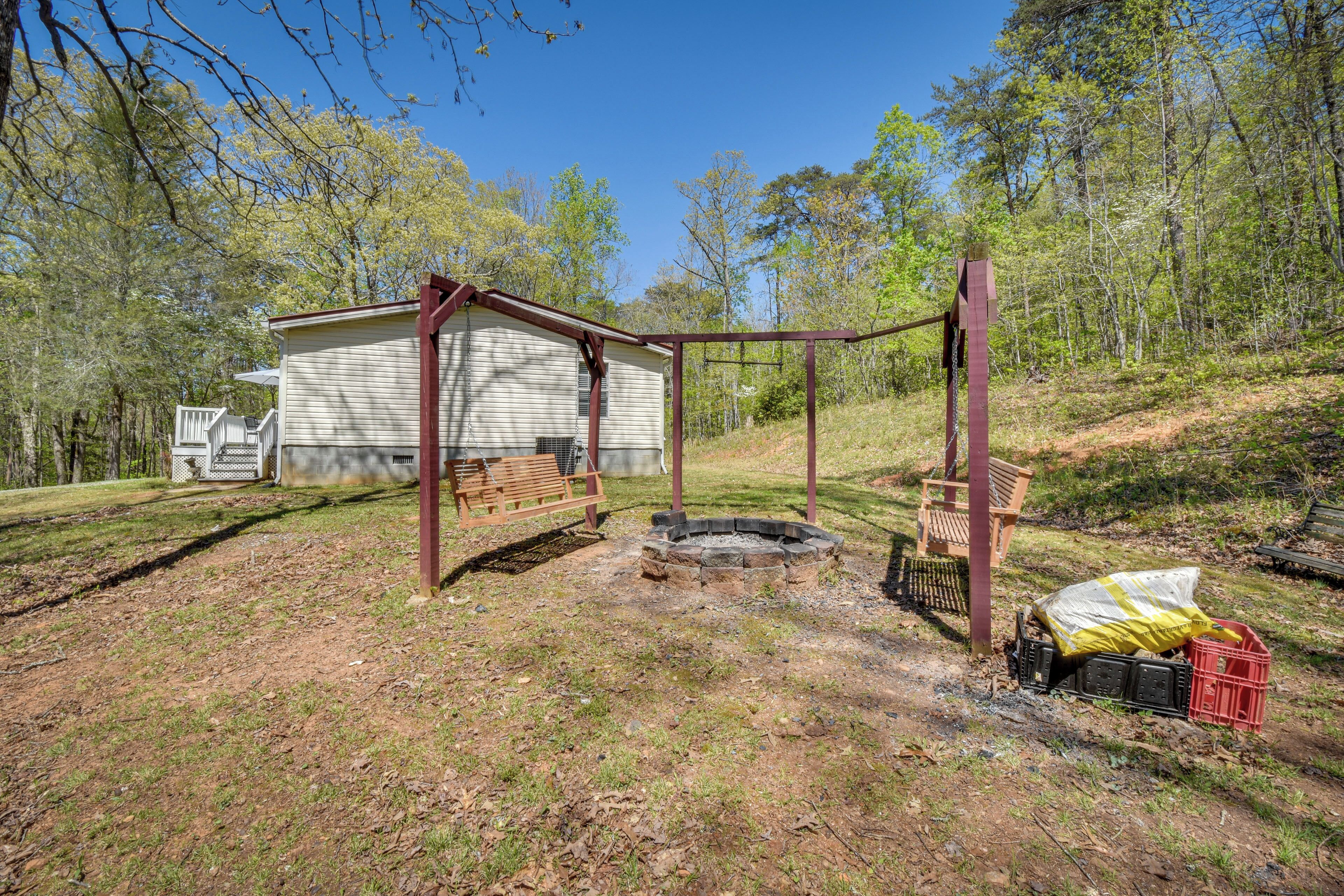 Une cabane dotée d’une terrasse en bois, d’un foyer et d’un banc.
