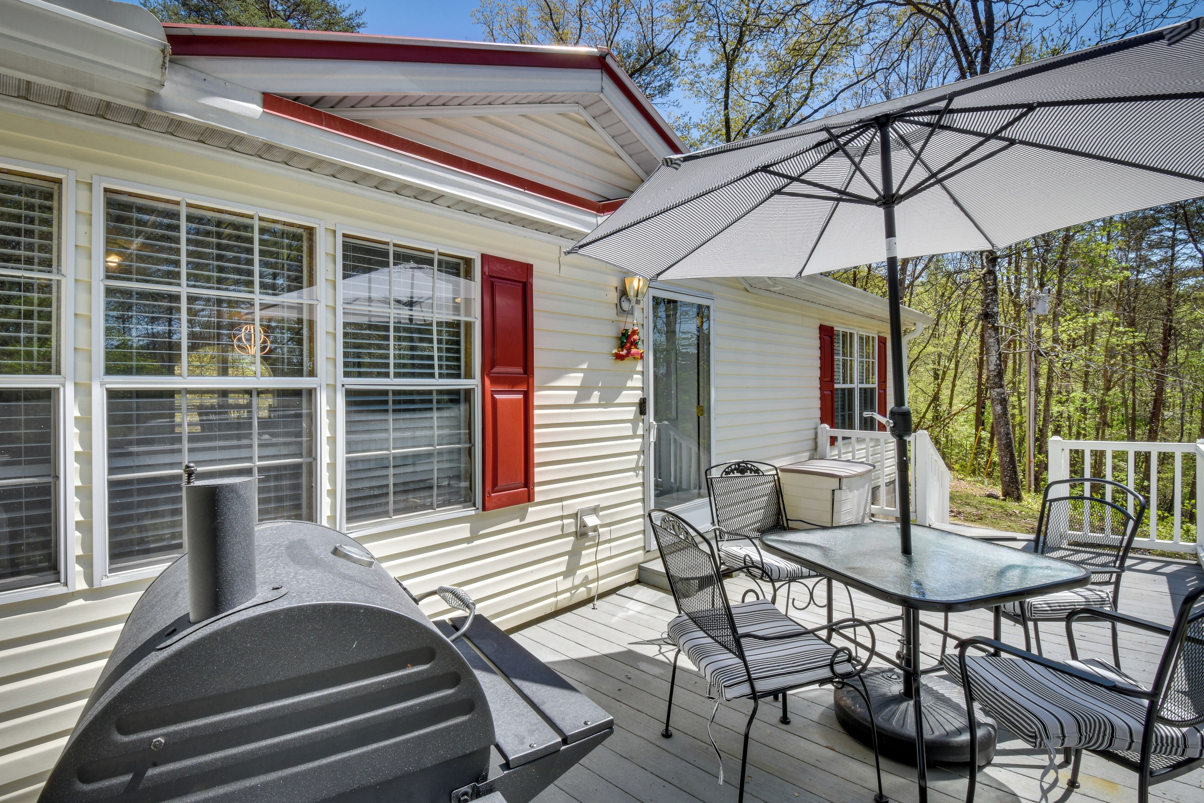 A covered outdoor patio with a grill, dining table, and chairs.