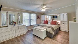 A bedroom with a bed, a dresser, a vanity with mirrors, a ceiling fan, and a window with blinds. - Walk to Lake Chatuge! Hayesville Cabin w/ Fire Pit (Hayesville)