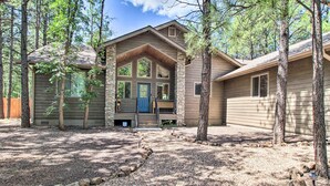 A cabin with a stone foundation, a front porch, and a large front door. - Fire Pits, Spacious Yard: Wooded Pinetop Escape! (Pinetop)