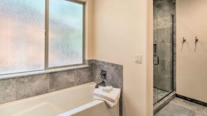 A bathroom with a bathtub, a glass shower enclosure, and a window. - Fire Pits, Spacious Yard: Wooded Pinetop Escape! (Pinetop)