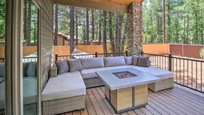 A covered deck with a built-in seating area and a fire pit. - Fire Pits, Spacious Yard: Wooded Pinetop Escape! (Pinetop)
