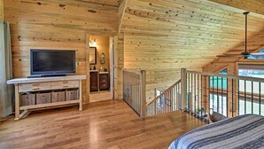 Un intérieur en bois avec un téléviseur posé sur un meuble en bois, un escalier et un lit.