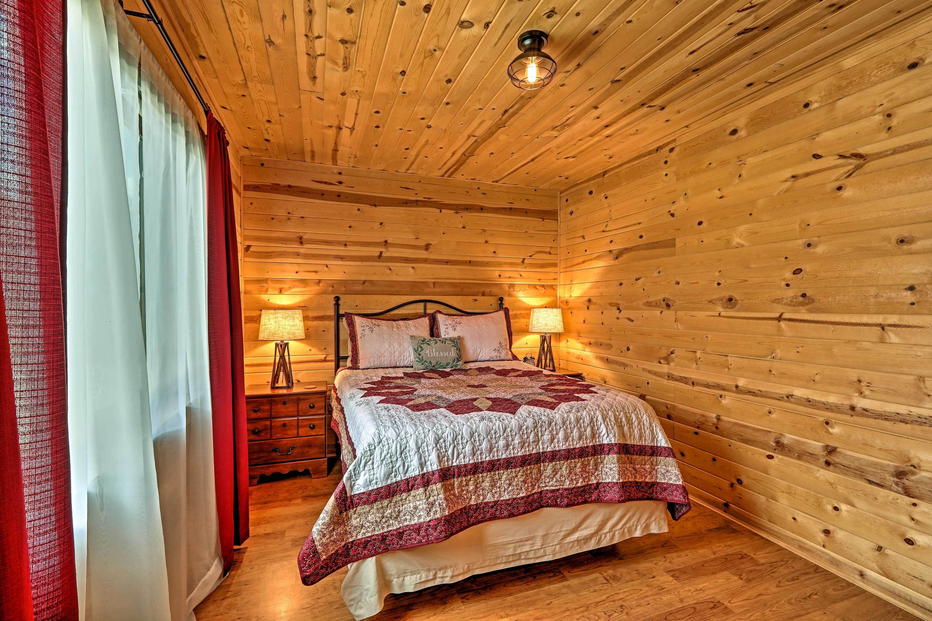 A wooden-paneled room with a bed, two bedside lamps, and a nightstand.